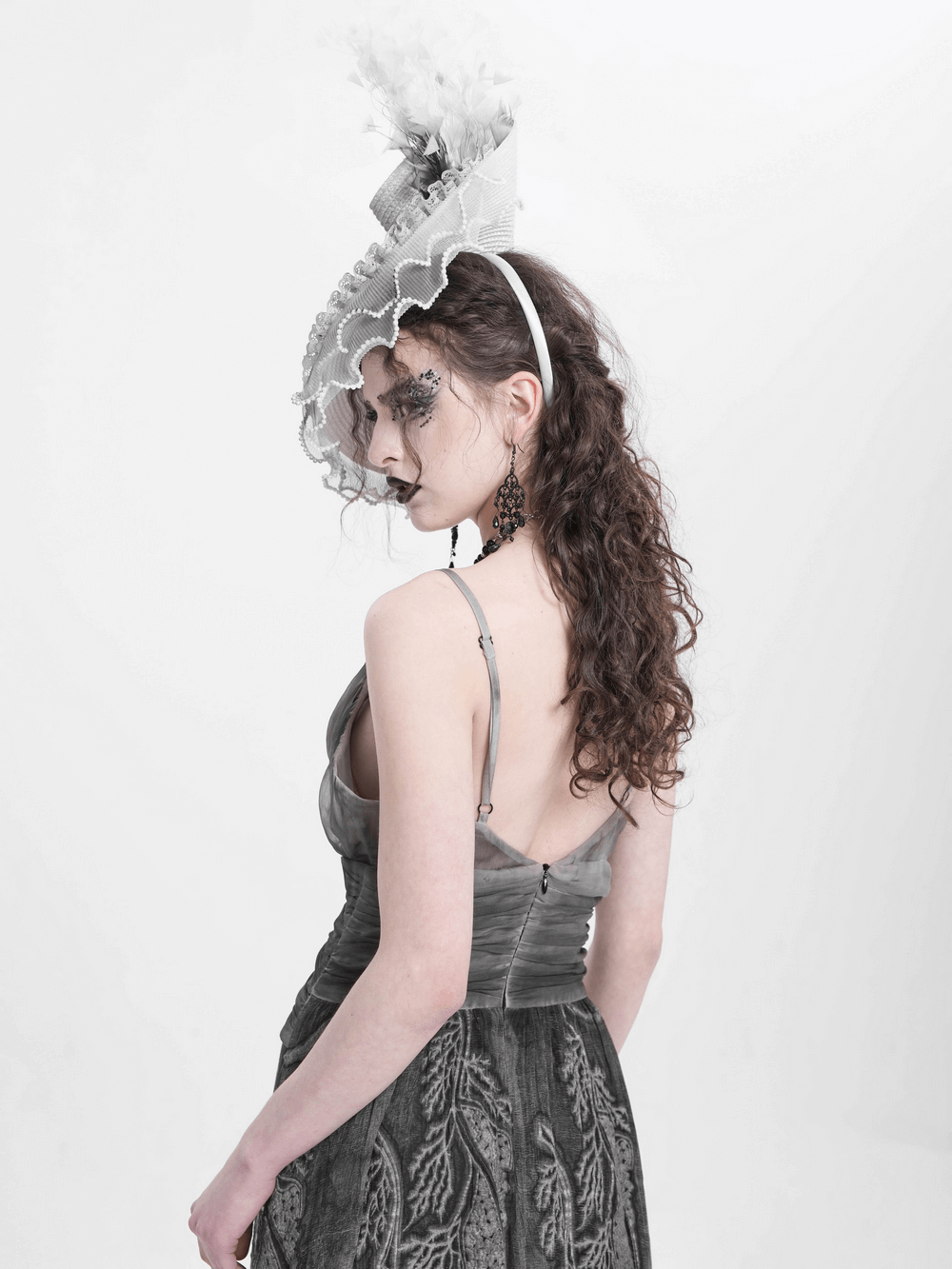 Gothic black and white floral fascinator hat with feathers worn by a model in a vintage-inspired outfit.