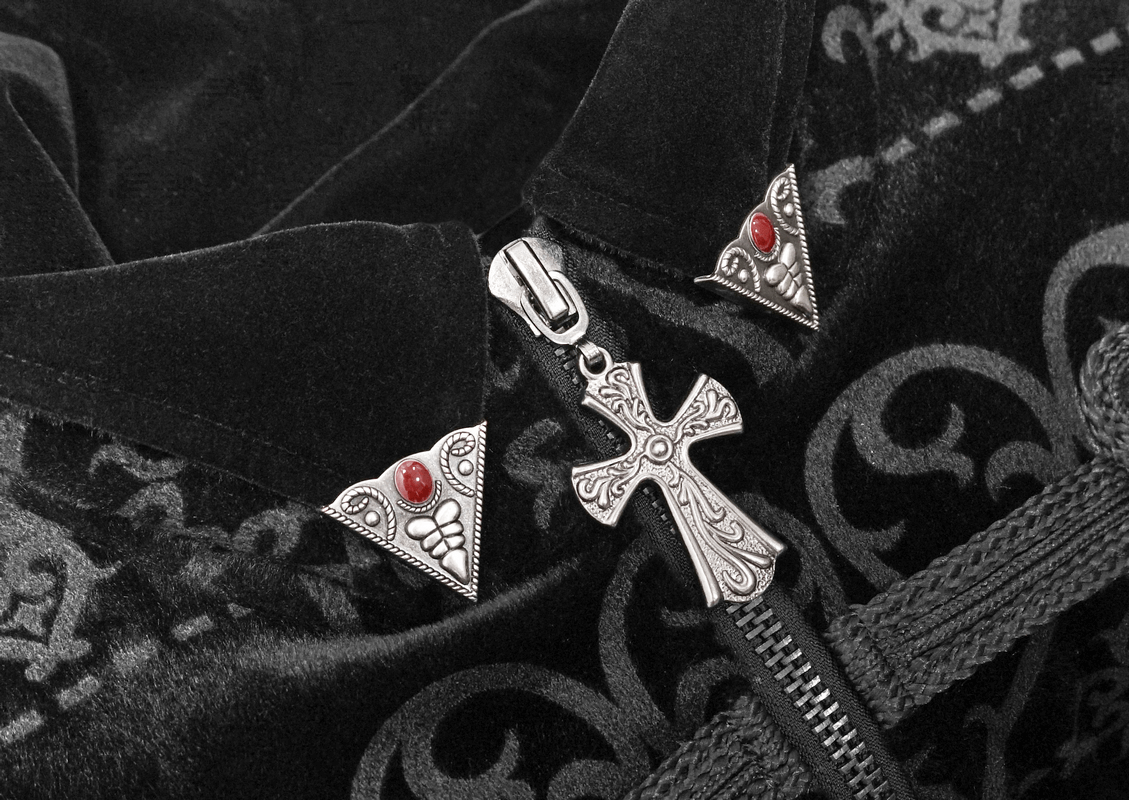 Close-up of elegant black coat with pointed shoulders, featuring silver engraved buttons and gothic-style appliques.