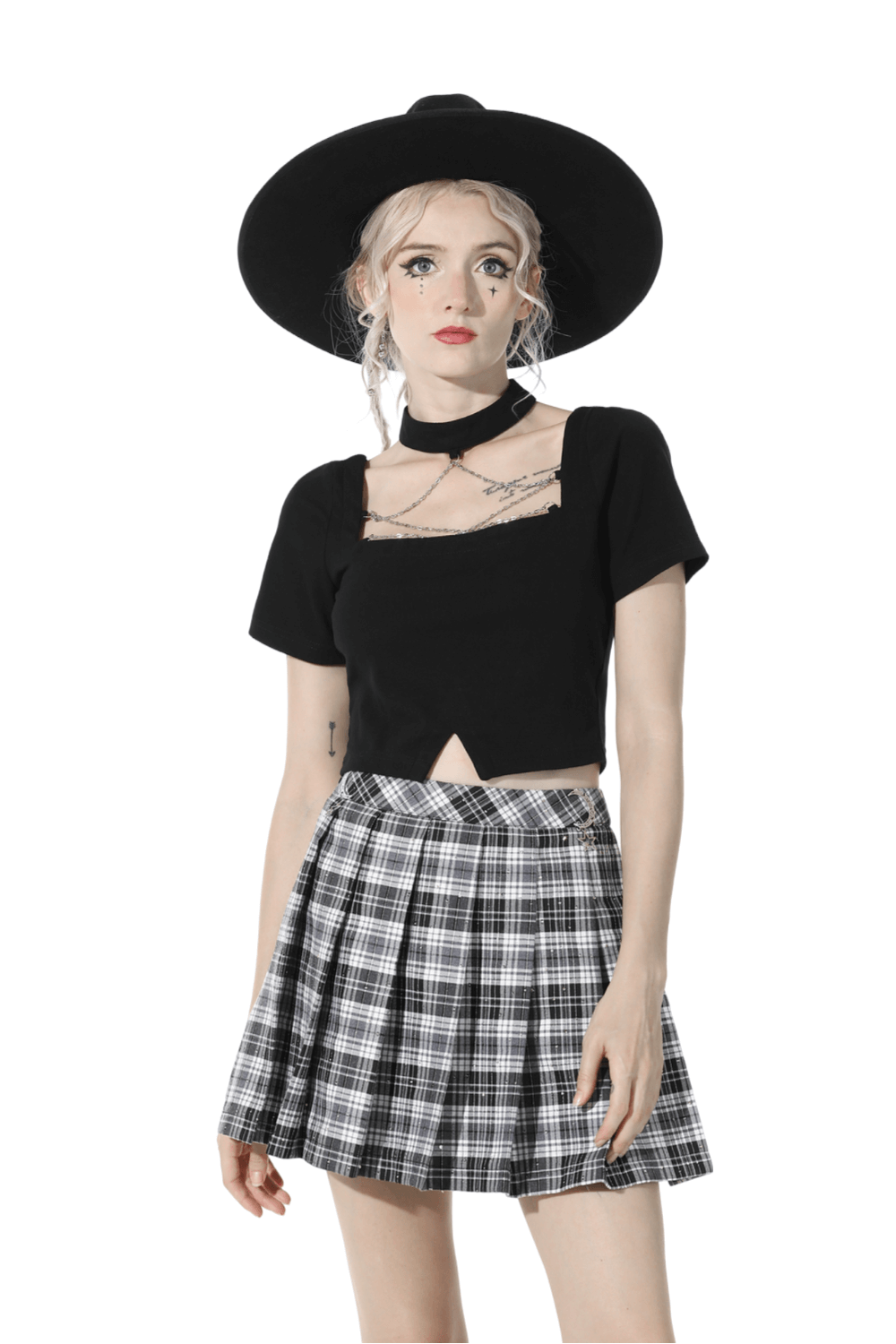 Chic model wearing an elegant black crop top and plaid skirt with a stylish black hat, showcasing modern fashion.