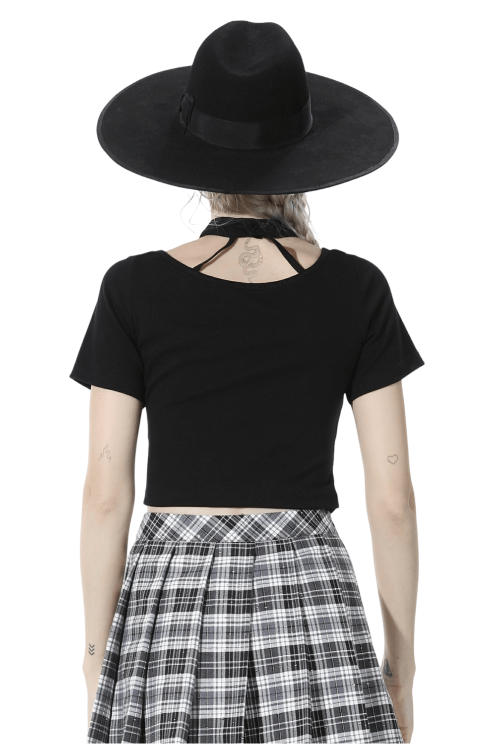 Elegant black crop top with unique neckline, paired with stylish hat and plaid skirt for a chic look.