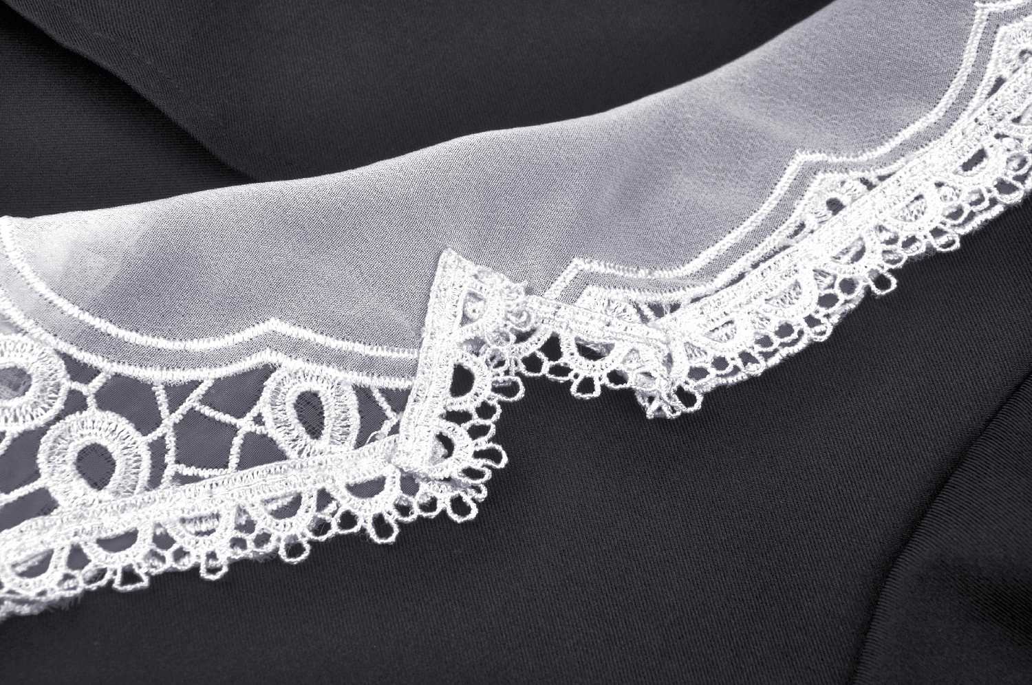 Close-up of elegant black dress lace collar detail with intricate white lace accents.