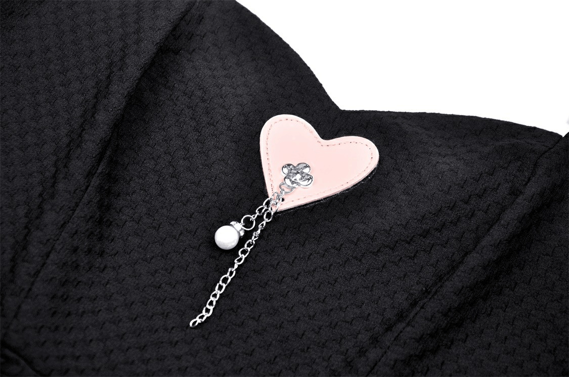 Close-up of heart pendant detail on elegant black dress with pink ribbon and silver chain. Perfect for special occasions.