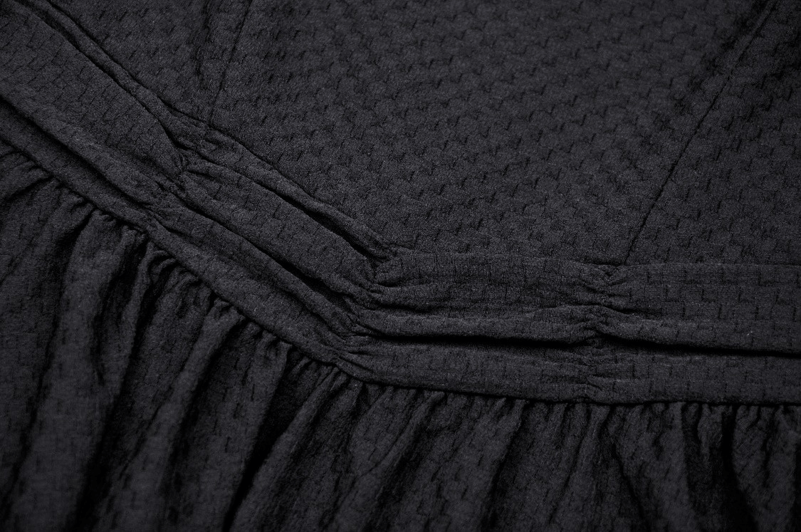 Close-up of elegant black dress fabric showcasing texture and gathered detailing for a chic party look.