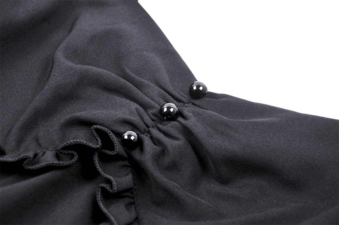 Close-up of black dress fabric showcasing unique strappy detail and elegant accents.