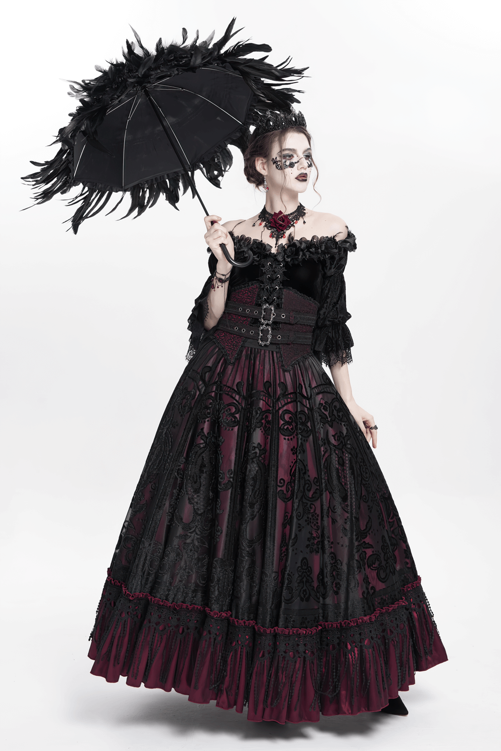 Elegant woman in a Gothic dress holding a black feathered umbrella, showcasing dark fashion style.