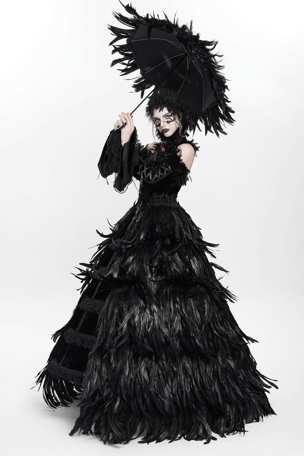 Elegant model in a black feathered gown holding a Gothic umbrella with beaded details, exuding a dark romantic vibe.