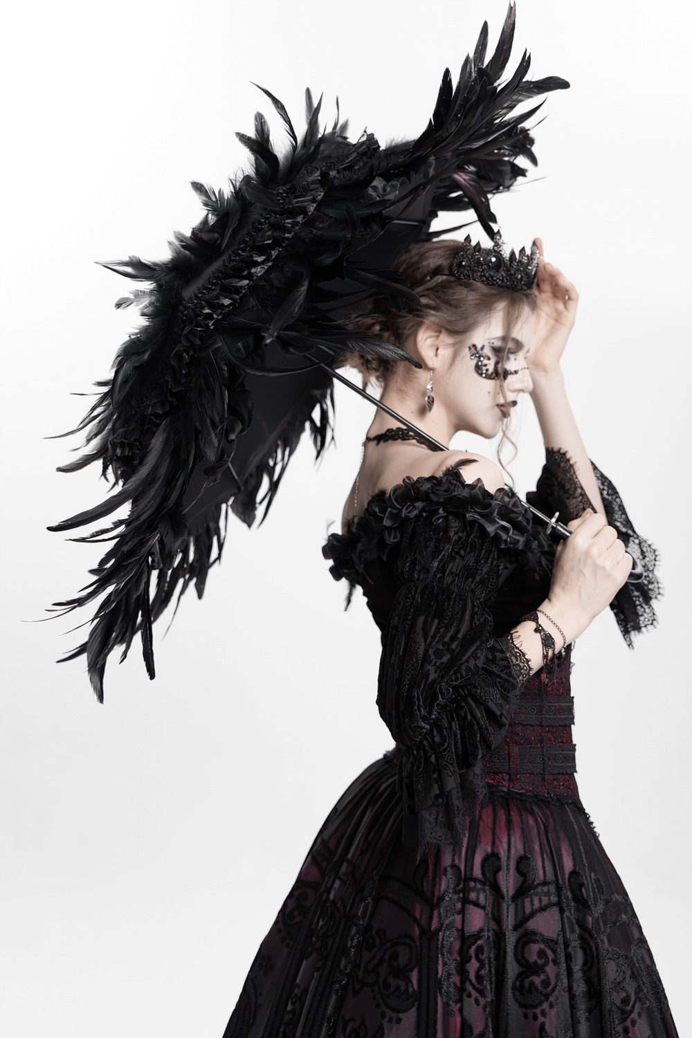 Elegant black feathered Gothic umbrella held by a woman in a Victorian-style dress, embodying dark romantic fashion.