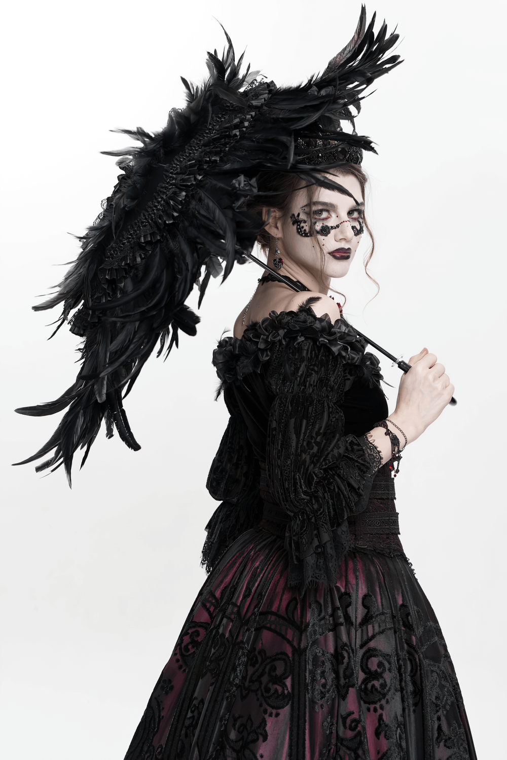 Elegant Gothic model with a feathered black umbrella, showcasing dark fashion and intricate lace details.