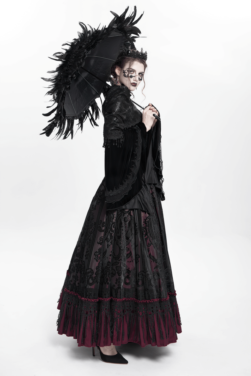 Elegant model holding a black feathered gothic umbrella, embodying dramatic and romantic dark fashion style.