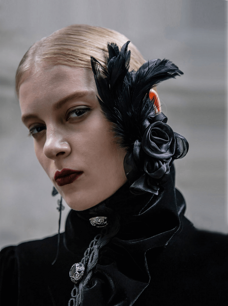 Elegant black flower hair clip with feathers worn by a model, highlighting gothic fashion accessories.