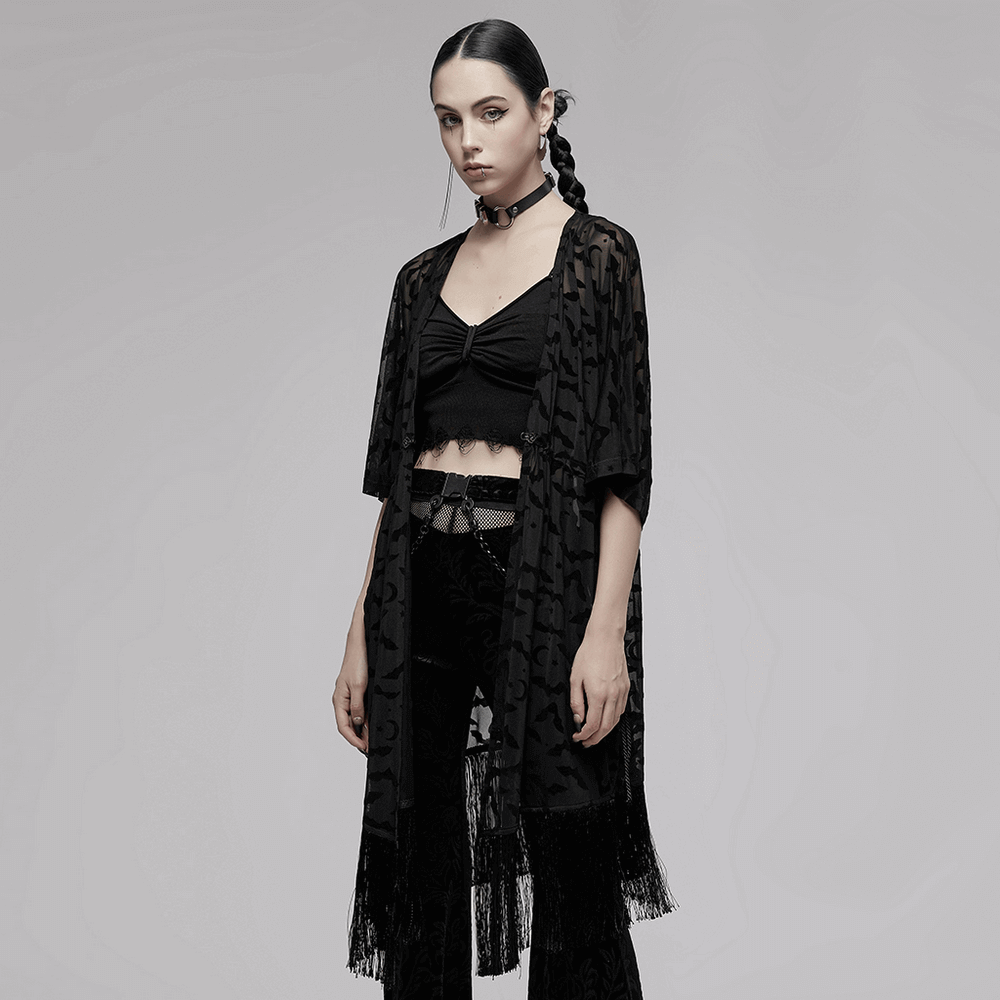 Elegant black lace kimono-cape with bat print, tassels, and gothic flair, worn casually by a model.