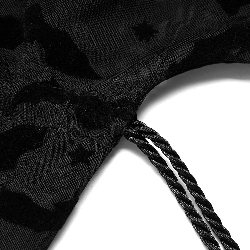 Close-up of the black lace fabric with bat and star patterns and drawstring detail of the kimono cape.