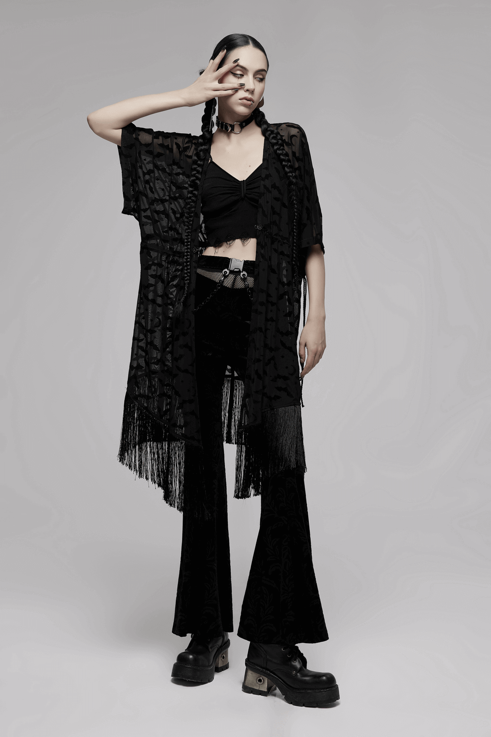 Model showcasing an elegant black lace bat print kimono-cape with tassels, styled with black flared pants.