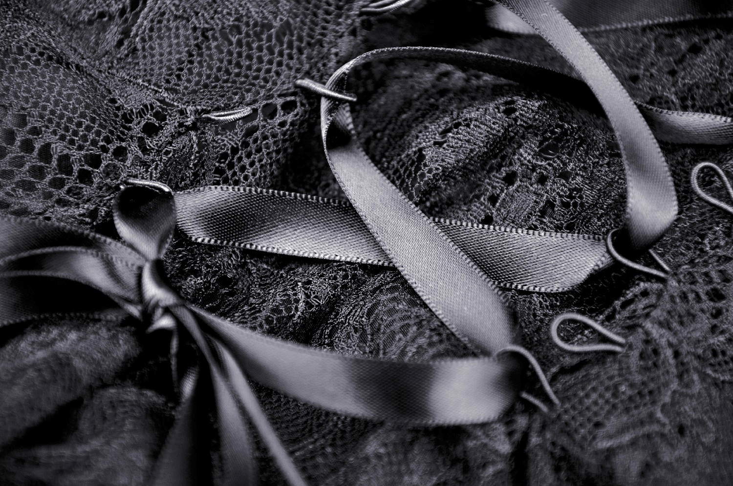 Elegant black lace fabric adorned with satin ribbon accents, showcasing rich textures and dark romantic vibes.