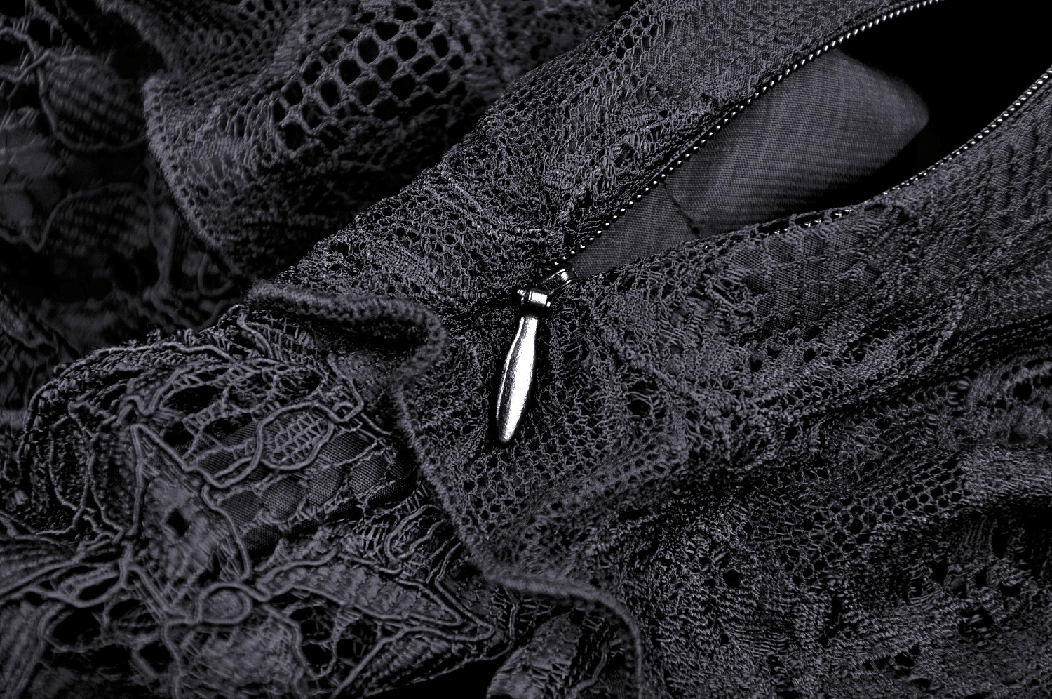Close-up of elegant black lace fabric with intricate patterns and a stylish zipper pull, ideal for gothic fashion.