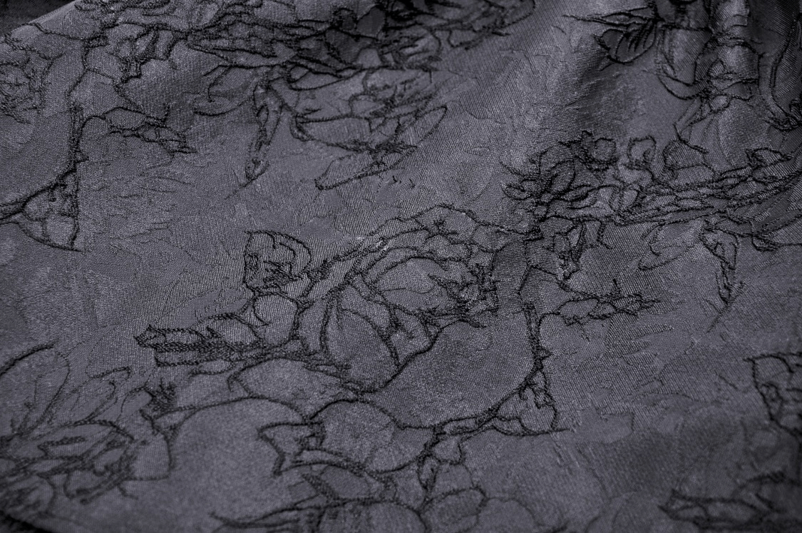 Close-up of black lace fabric with floral detailing, perfect for elegant evening wear.