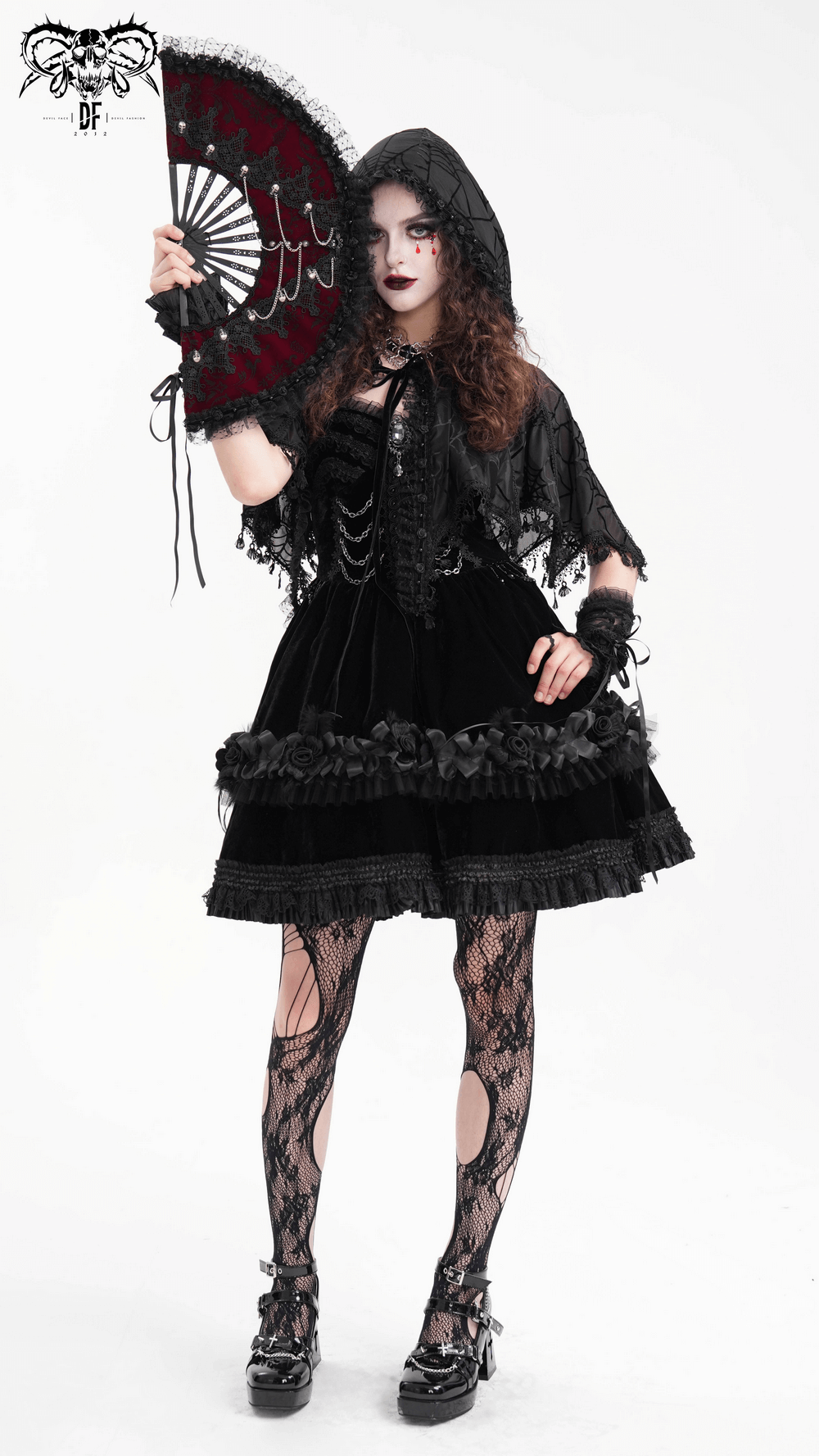 Gothic woman in a black lace dress holding a decorative fan, showcasing intricate layers and lace stockings against a white background.