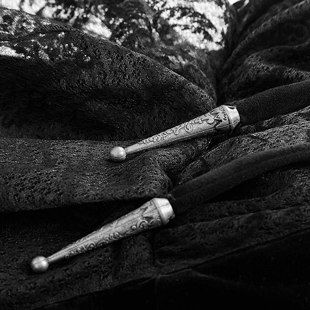 Close-up of ornate silver clasps on an elegant black lace cloak, adding gothic charm to mystical fashion.