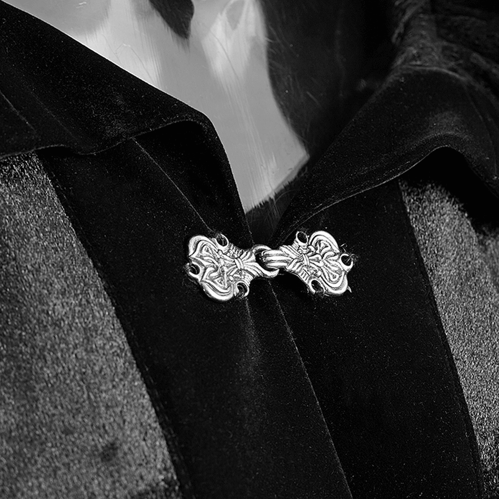 Close-up of a silver ornate clasp on an elegant black velvet hooded cloak.