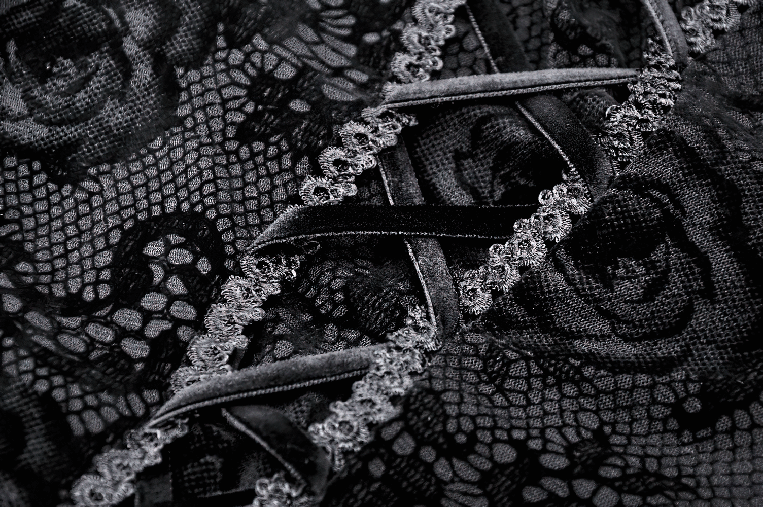 Close-up of intricate black lace detailing with floral patterns and elegant velvet ribbons.