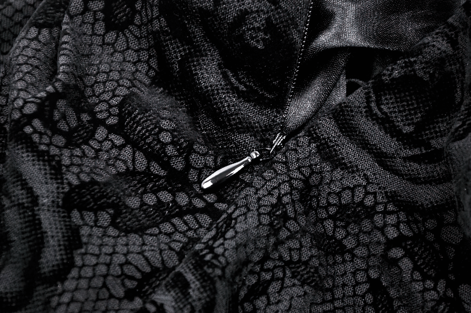 Close-up of black lace fabric showcasing intricate floral patterns and a stylish zipper detail.