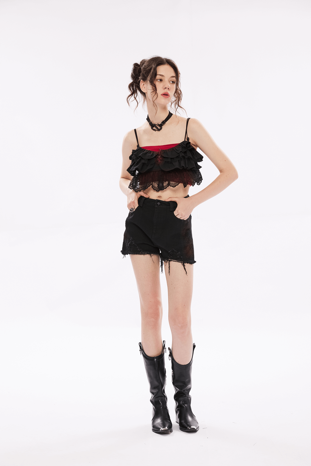 Model wearing an elegant black lace off-the-shoulder crop top with ruffles, paired with shorts and stylish black boots.