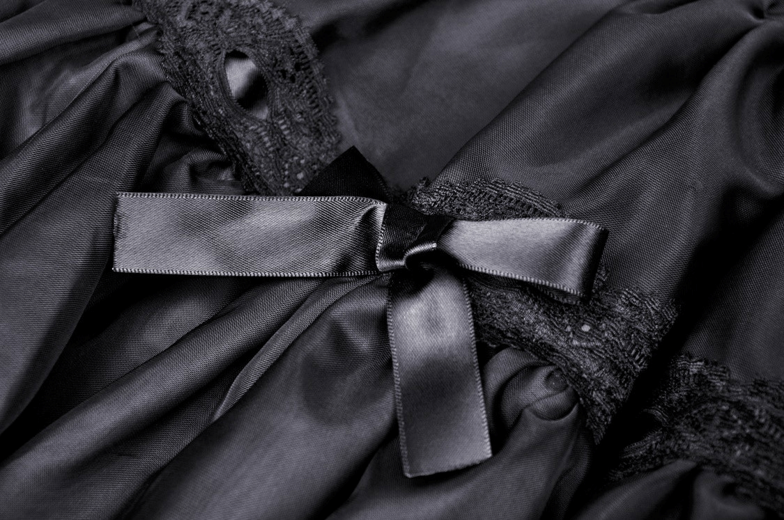 Close-up of a black lace skirt showcasing intricate lace patterns and a delicate bow detail for an elegant evening look.