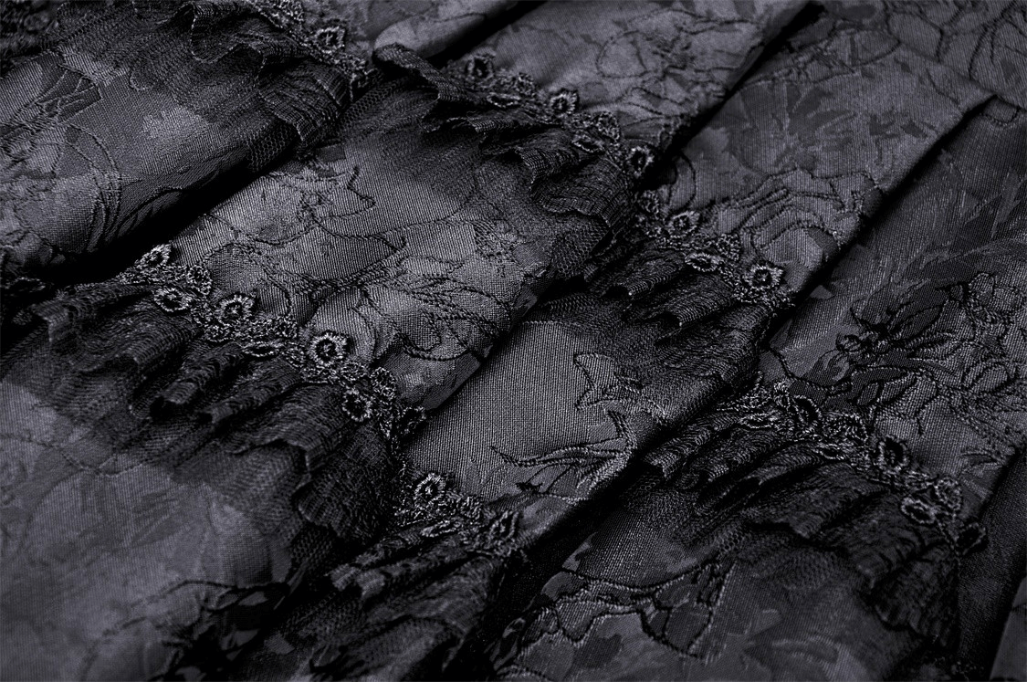 Close-up of elegant black lace fabric showcasing tiered design and intricate detailing for evening wear.