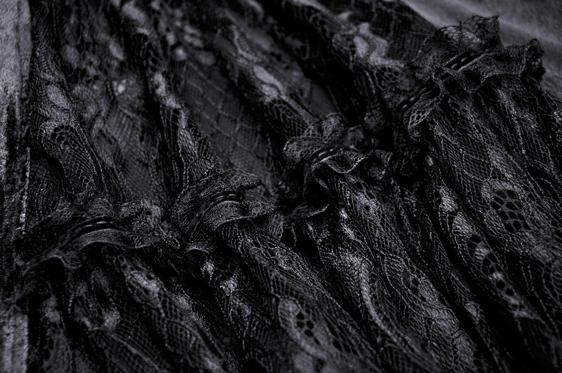 Close-up of intricate black lace fabric showcasing detailed embroidery and gothic design for evening wear.