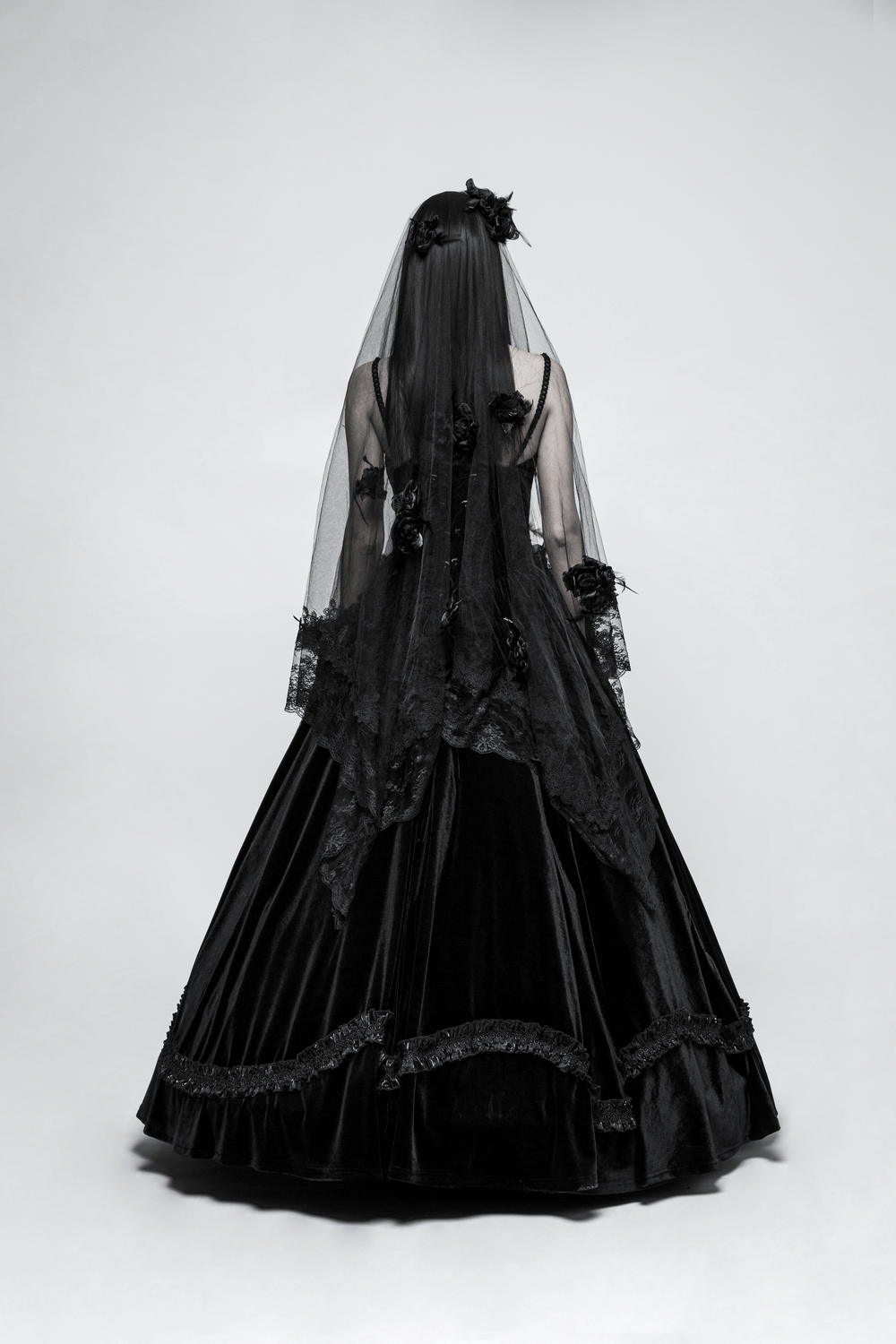 Elegant black lace wedding veil with 3D roses, flowing over a dramatic black velvet gown.