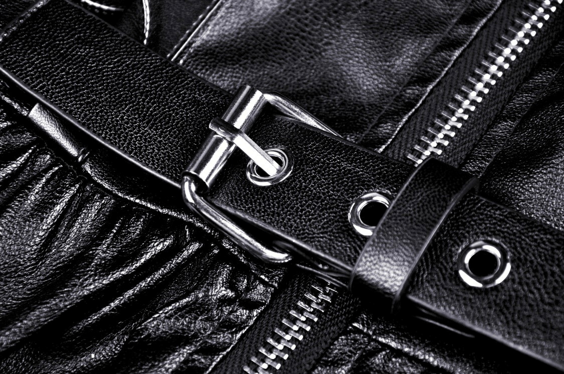 Close-up of elegant black leather dress belt with buckle detail and ruffled fabric, showcasing stylish design.