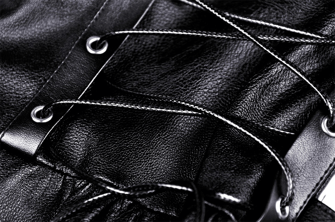 Close-up of black leather dress lacing showcasing ruffled design and adjustable straps for a stylish look.