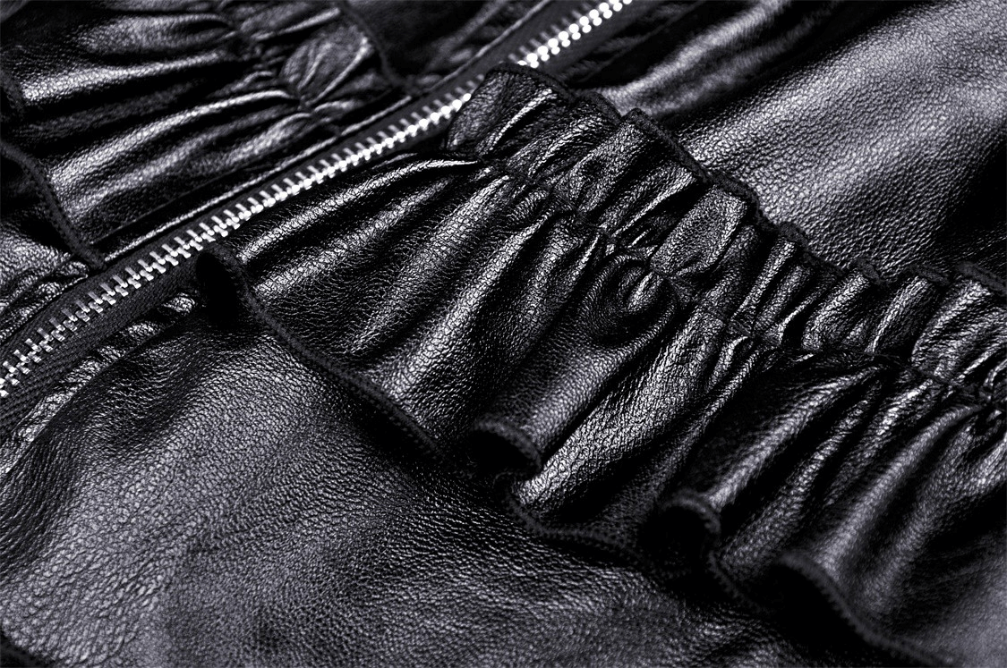 Close-up of stylish black leather fabric with ruffled layers and zippers, showcasing elegance and sophistication.