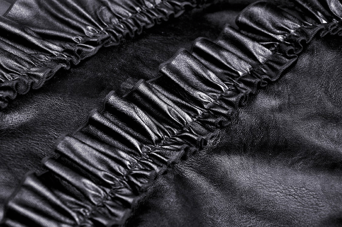 Close-up of elegant black leather with stylish ruffled layers, showcasing texture and sophistication.
