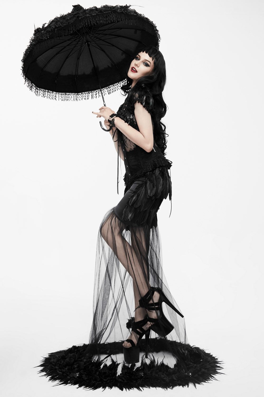 Stylish model in a black gothic long skirt with flared mesh and umbrella, showcasing elegance and dramatic flair.