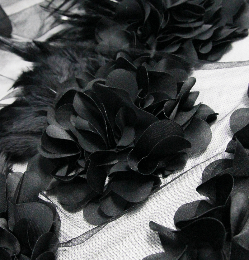 Close-up of elegant black fabric flowers on a gothic dress, showcasing intricate textures and layers for a stylish look.