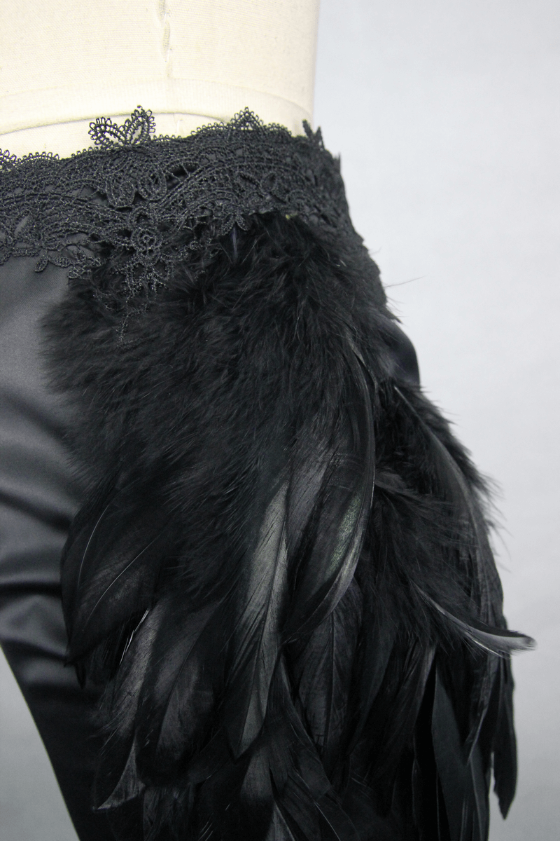 Close-up of luxurious black skirt with lace and feather details, showcasing gothic elegance and unique fashion design.