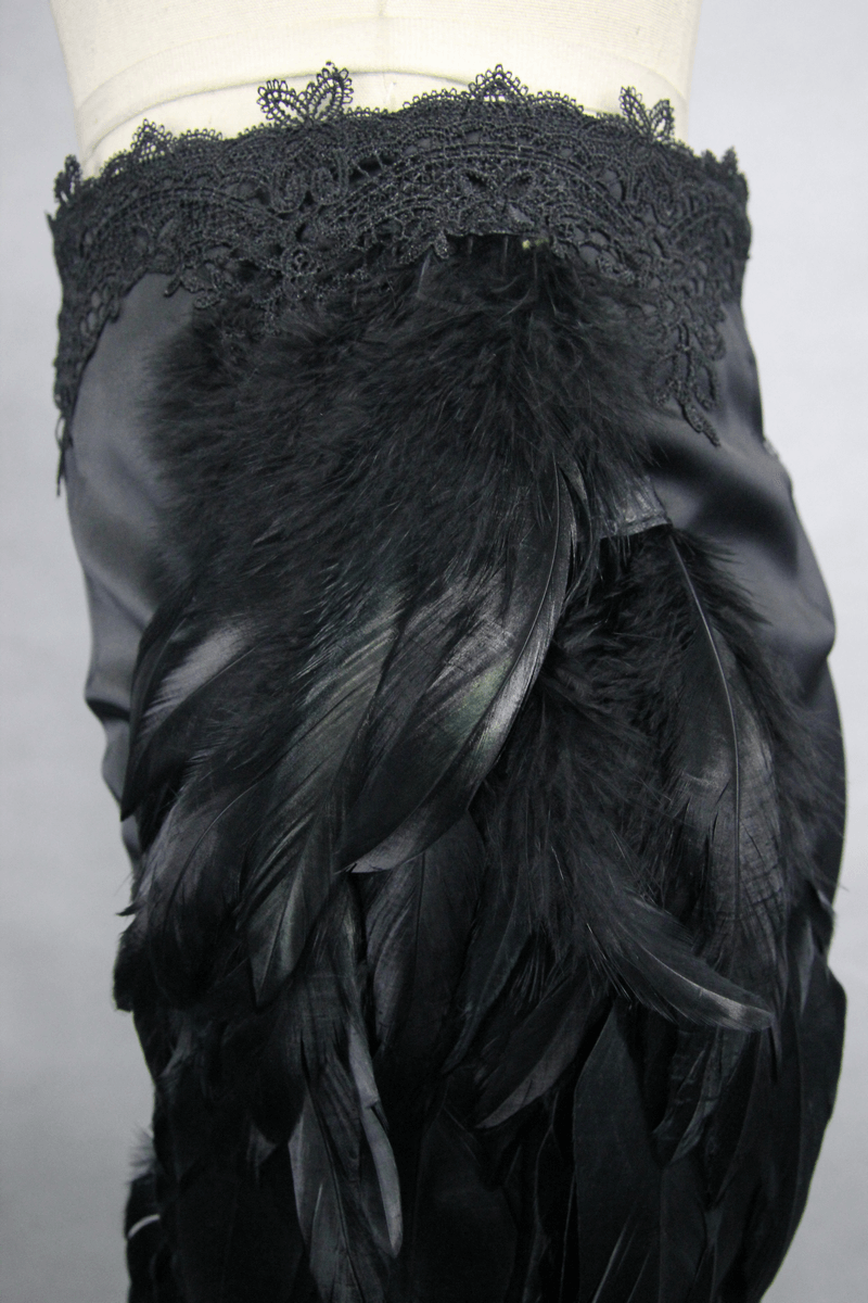 Close-up of elegant black skirt with feather accents and lace waistband, showcasing gothic style and intricate details.