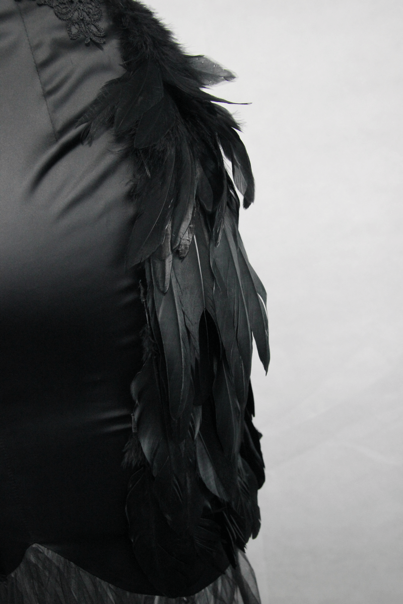 Close-up of elegant black skirt with feather embellishments, showcasing gothic style and textures.