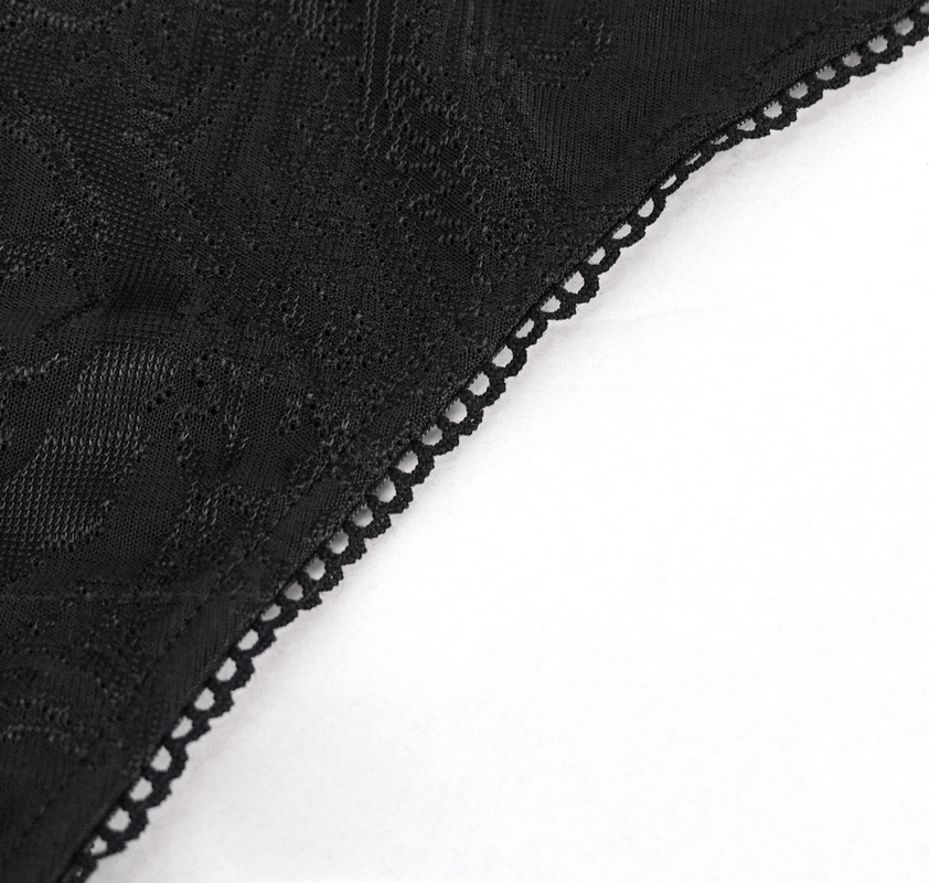 Close-up of elegant black fabric with intricate brocade pattern and fringed lace trim for gothic-style swimwear.