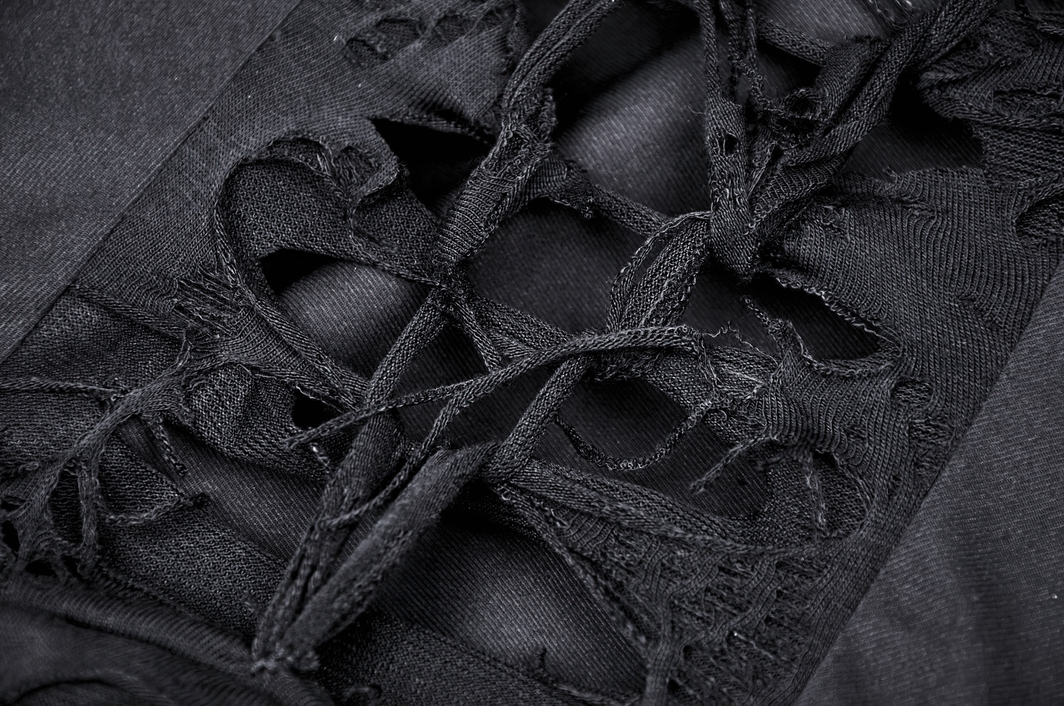 Close-up of intricate lace-up detailing on the bodice of an elegant black torn dress.