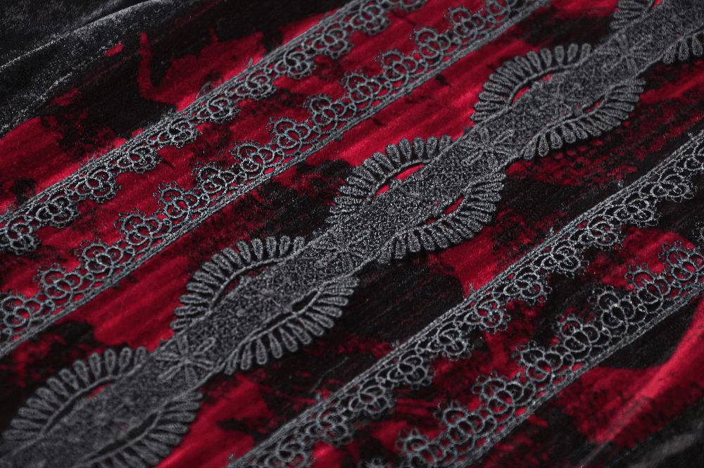 Close-up of elegant black velvet fabric with red lace details, showcasing intricate gothic texture and design.