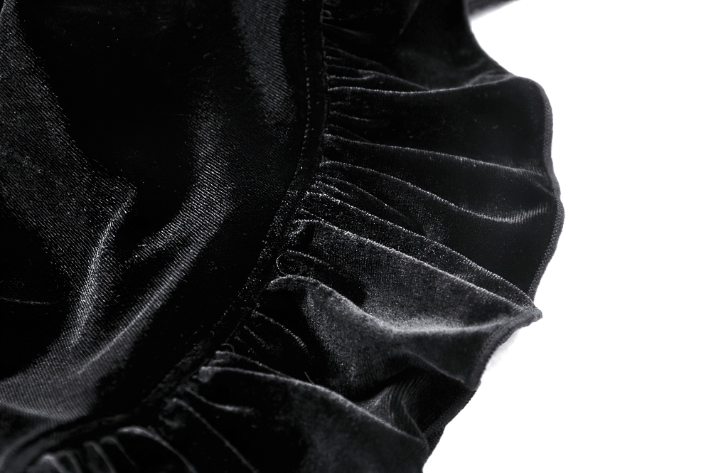 Close-up of luxurious black velvet fabric showcasing ruffled texture for elegant dress details.