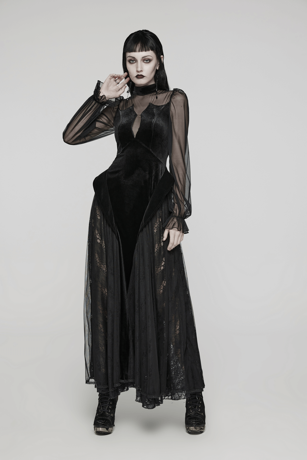 Model in an elegant black velvet mesh dress with sheer sleeves and gothic charm, perfect for a dramatic look.