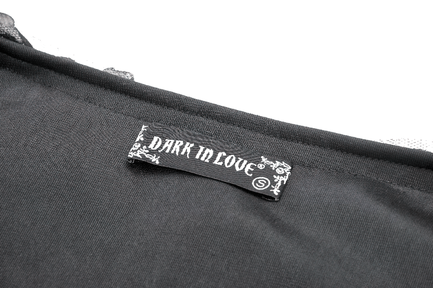 Close-up of Dark in Love brand label on black fabric, showcasing gothic fashion elegance.