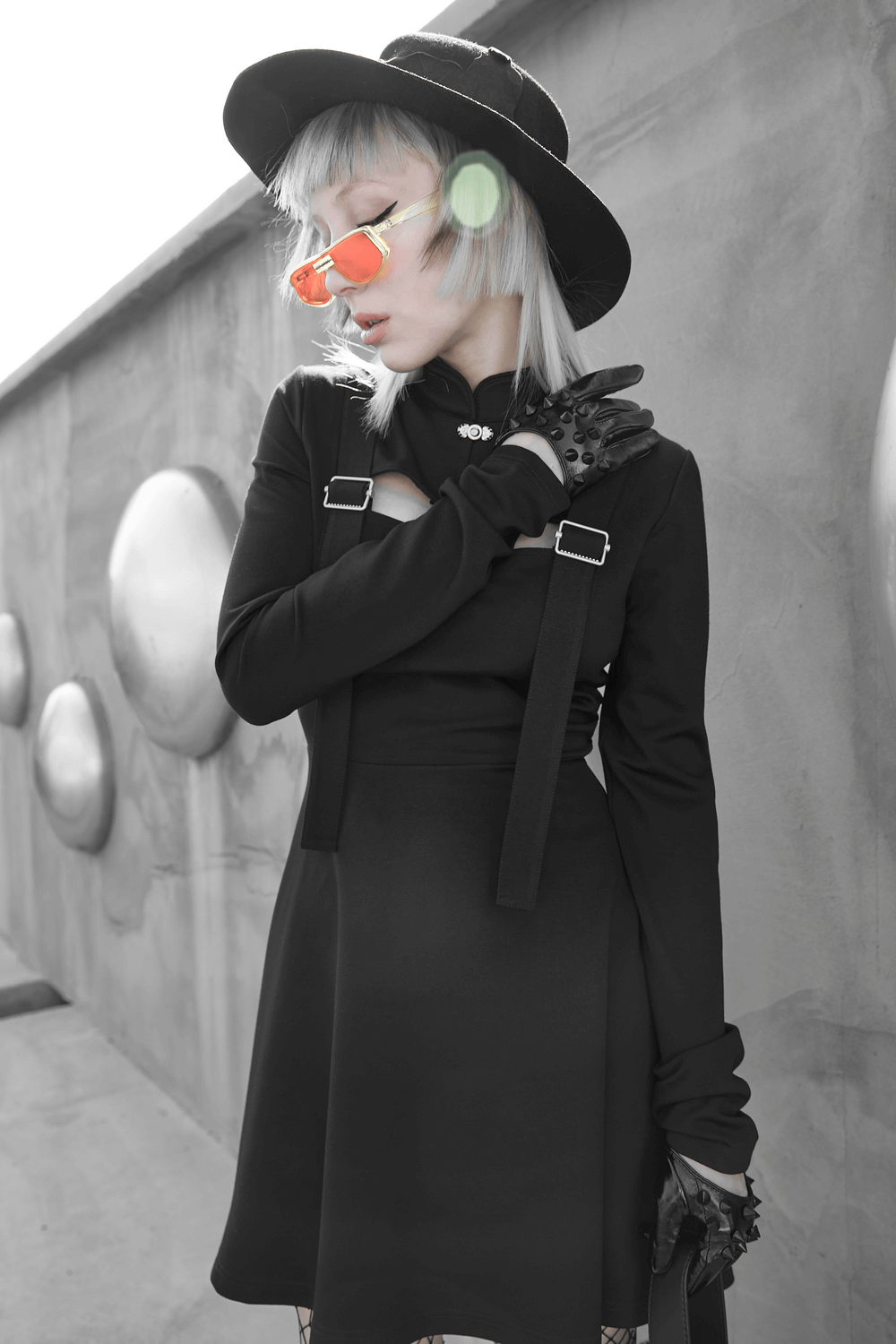 Stylish model in black dress and spiked punk half-hand gloves, showcasing edgy punk-inspired fashion.