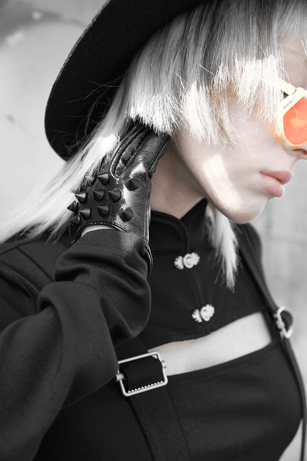 Stylish model wearing black spiked punk half-hand gloves with sunglasses and a hat for a chic edgy look.
