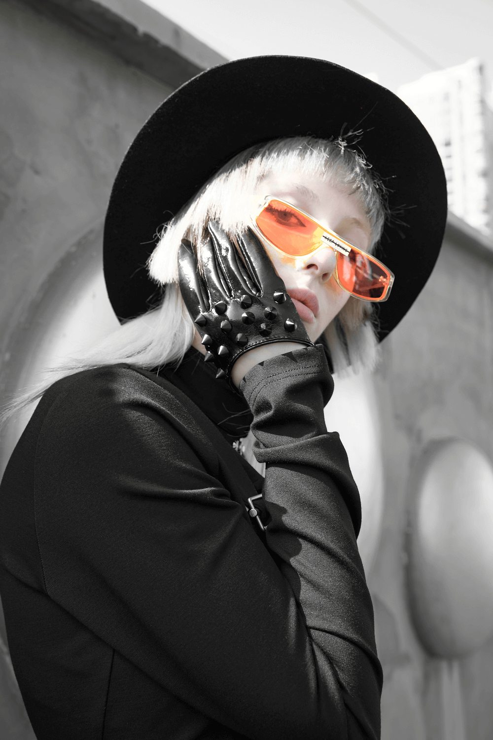 Model wearing elegant chic black spiked punk half-hand gloves and orange sunglasses, showcasing edgy style.