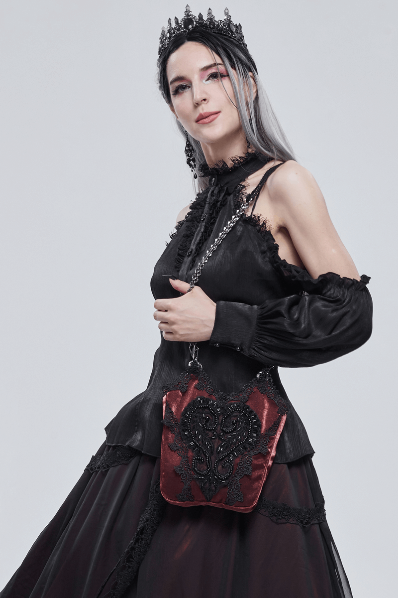 Elegant gothic woman in a black dress holding a red floral bucket bag with guipure and chain.