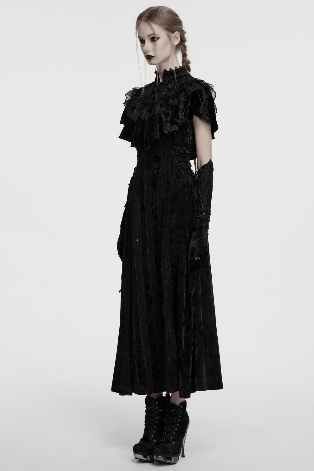 Model wearing an elegant black velvet goth dress with ruffles and lace detailing, showcasing a striking vintage style.